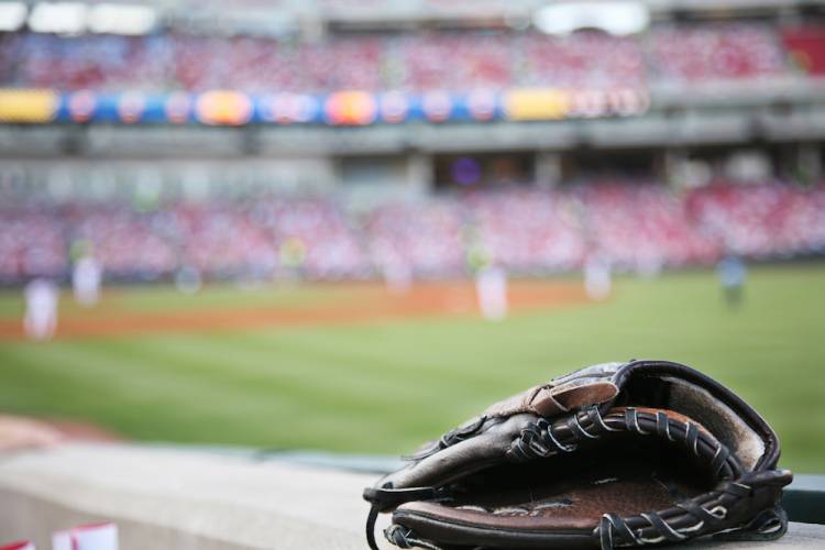 Baseball glove in foreground with blurry baseball stadium in the background